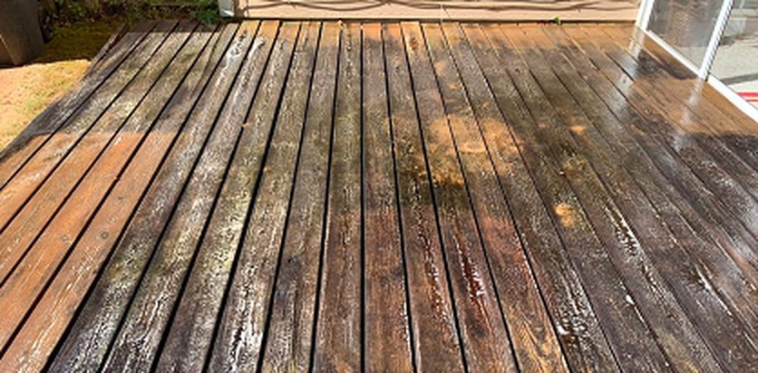 The same deck boards dark with weathered buildup before cleaning