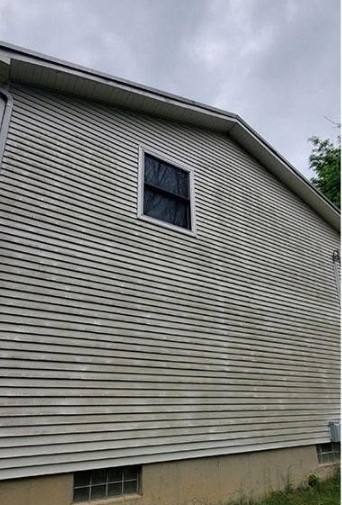 House siding dulled by grime and organic growth before soft washing